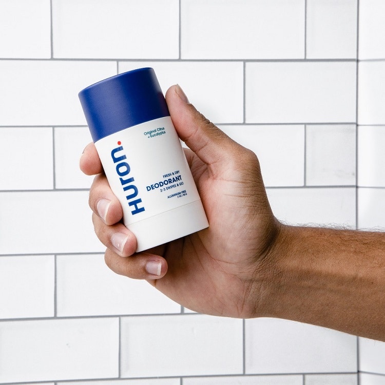 man holding deodorant in shower